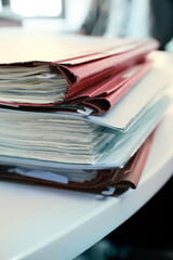 A pile of paper documents on a white desk.