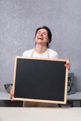 Woman holds chalk board in her hands and laughs. Copy space, mock up. Vertical frame