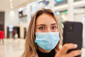 Woman with face mask uses coronavirus warning app