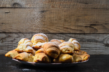 Homemade cookies in the form of bagels with jam filling sprinkled with powdered sugar on a wooden background.