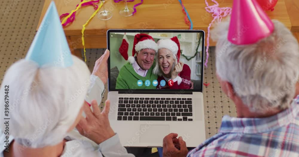 Canvas Prints Caucasian senior couple wearing party hats on laptop video chat during christmas at home