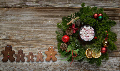 multicolored gingerbread men on an old wooden table next to a Christmas wreath. Christmas and holiday concept. High quality photo