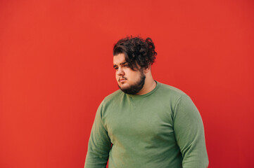 Portrait of a fat bearded hispanic guy with a stylish haircut and curly hair, standing in front of...
