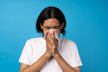 Sick guy has runny nose. Asian man blowing out nose with napkin. Fever, runny nose, sore throat,...
