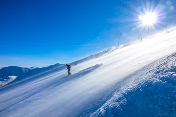 Fotobehang Skier on a Sunny Slope and Blizzard © goodman_ekim