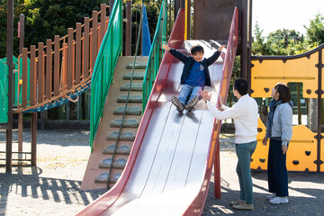 若い夫婦と子供が仲良く公園で遊んでいる