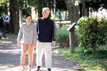 Obraz premium 高齢者の夫婦が仲良く公園をウォーキングしている