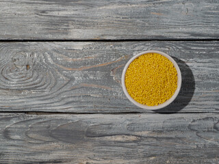 Cereal of millet in the bowl on wooden background.