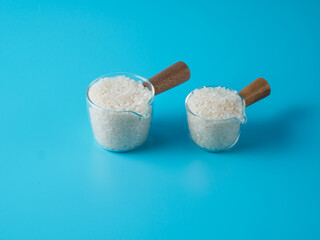 Raw rice in two small bowls on blue background.