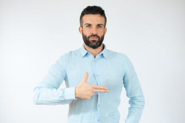 Young man wearing casual blue shirt pointing finger side over white background.