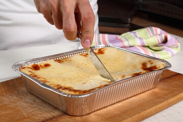 Cutting Lasagne Bolognese in Disposable Foil Dish