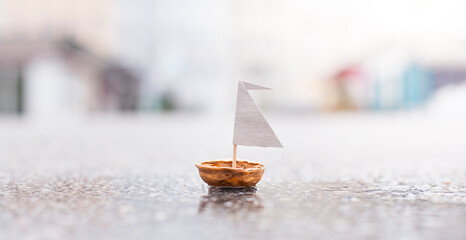 A small boat made of nut shell sailing on street.
Kleines Boot aus Nussschale schwimmt auf der...