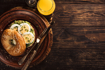 Healthy freshly baked bagel filled with boild eggs, avocado and chives. Breakfast food concept with copy space