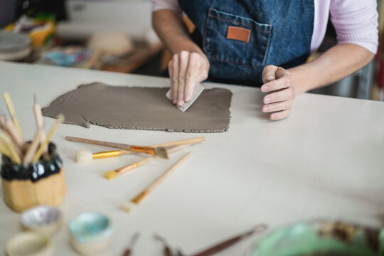 Woman making ceramics objects inside creative pottery studio - Art and workshop concept - Focus on right hand
