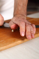 Chef pressing down sliced garlic by knife blade. Making Chicken and Egg Galette Series.