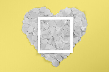 Elegant and tender gray heart of scattered heart-shaped confetti with white frame on illuminating yellow background. The mood of tenderness and love. Main color trend of the year 2021.