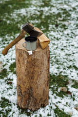 Eine Teetasse und eine Axt auf einem Holzstock. Holz Hacken, Winter, Schnee.