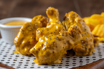 Baked chicken wings with sesame and sauce on wooden background
