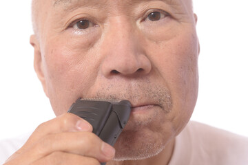 電気シェーバーで髭を剃る日本人シニア男性
