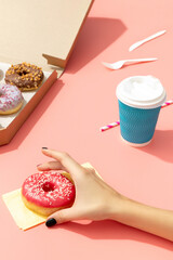 Set of yummy colorful donuts in paper box on pink background