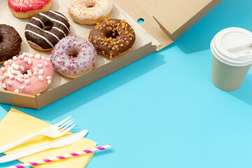 Set of yummy colorful donuts in paper box on blue background