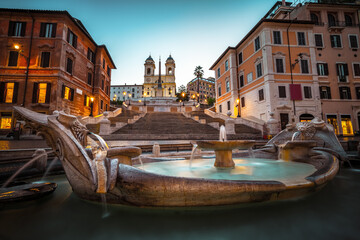 Fountain on the Piazza di Spagna square and the Spanish Steps in Rome at dusk