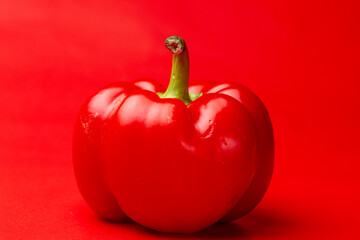 Monochrome radiant deep red frame of clean background with vibrant Bell pepper or fresh paprika in studio light with green stem rising above