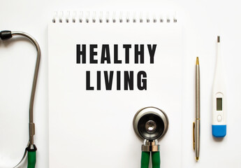 HEALTHY LIVING text written in a notebook lying on a desk and a stethoscope.