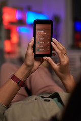 Close-up of woman resting on sofa and listening to music online on her mobile phone