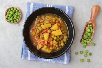 Indian popular homemade Aloo Matar. Potatoes and peas curry. Vatana batata bhaji or sabzi. with cooking ingredients along with copy space.