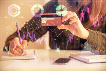Double exposure of woman on-line shopping holding a credit card and financial graph drawing. Stock market E-commerce concept.