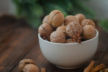 Close-up of bowl with walnuts on the wooden table with christmas tree winter branches