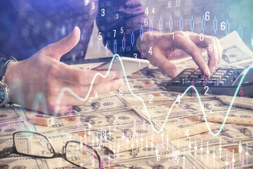 Double exposure of man's hands holding and using a digital device and forex graph drawing. Financial market concept.