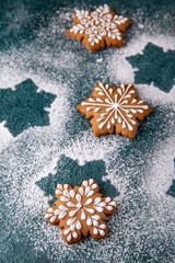 Christmas homemade gingerbread cookies in the shape of snowflakes and herringbone on a turquoise background. Holiday sweets for decoration and gifts.