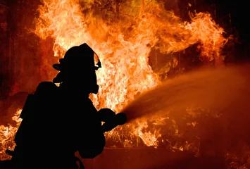 Poster Silhouette von Feuerwehrmännern, die ein wütendes Feuer mit Flammen bekämpfen. Waldbrand. © Artem