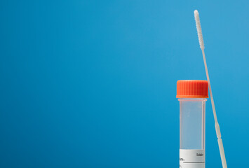 Swab (sample collection) with transport vial with orange cap, transparent with adhesive for data, with blue backgrond.