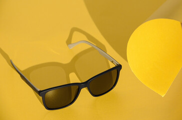 Black sunglasses on yellow background, copy space. Illuminating. Color of the year 2021. Top view,...