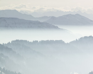 Snow Mountains in low lying inversion valley fog. Silhouettes of foggy Mountains and trees. Scenic...