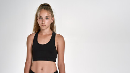 Portrait of cute sportive girl child in sportswear looking at camera, while posing isolated over white background