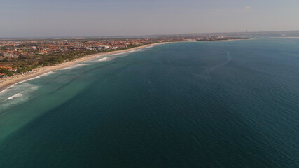 Aerial view sand beach with resting people, hotels and tourists, sun umbrellas, Bali, Kuta. surfers on water surface. Seascape, beach, ocean, sky sea Travel concept