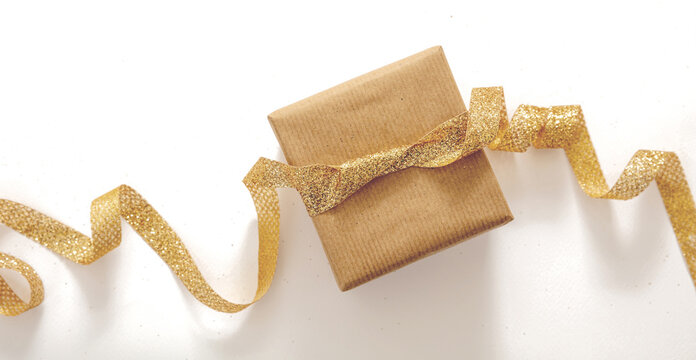 Christmas gift box and golden ribbon on white background, top view.