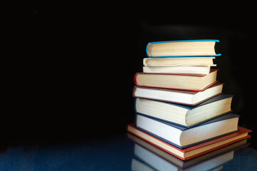 Stack of the books rests upon turn blue table with reflection