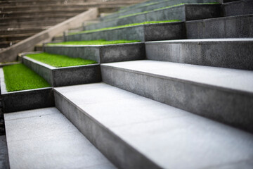 Neat and tidy grey stair steps made of stone and granite tiles with a curb, side by side with green...