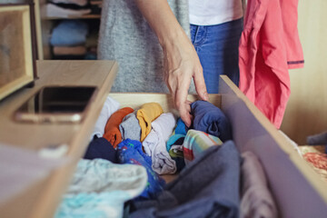 A woman is sorting through things in her home wardrobe with her hands. Folding clothes after washing. Household responsibilities, keeping the apartment clean and tidy