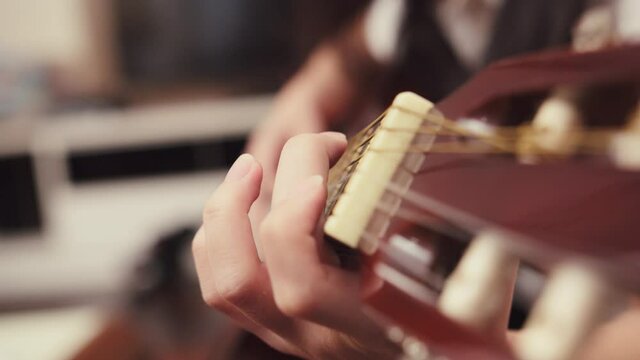 Close-Up of a guitar teacher guiding the student's fingers to press the correct strings on the guitar fret