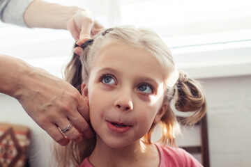 Mom is combing her daughter's hair. Taking care of baby's hair. The concept of a happy childhood and a good attitude towards children. Happy family