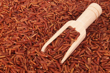 Red rice with wooden scoop close up