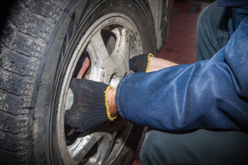 A man puts a wheel on a car. Seasonal tire replacement. Close up