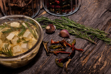 Cheese in butter with spices, garlic, rosemary and dried peppers on a wooden background.