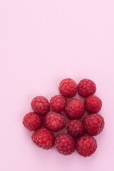 Red raspberries in a heart shape on pink background. Valentines day concept. vertical .